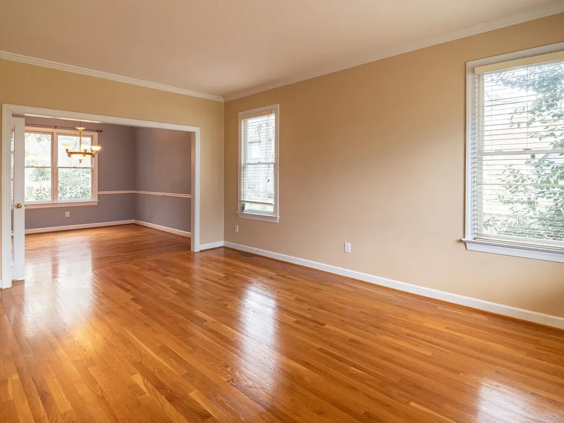 An empty, sunlit room with hardwood floors in a house that has been cleared