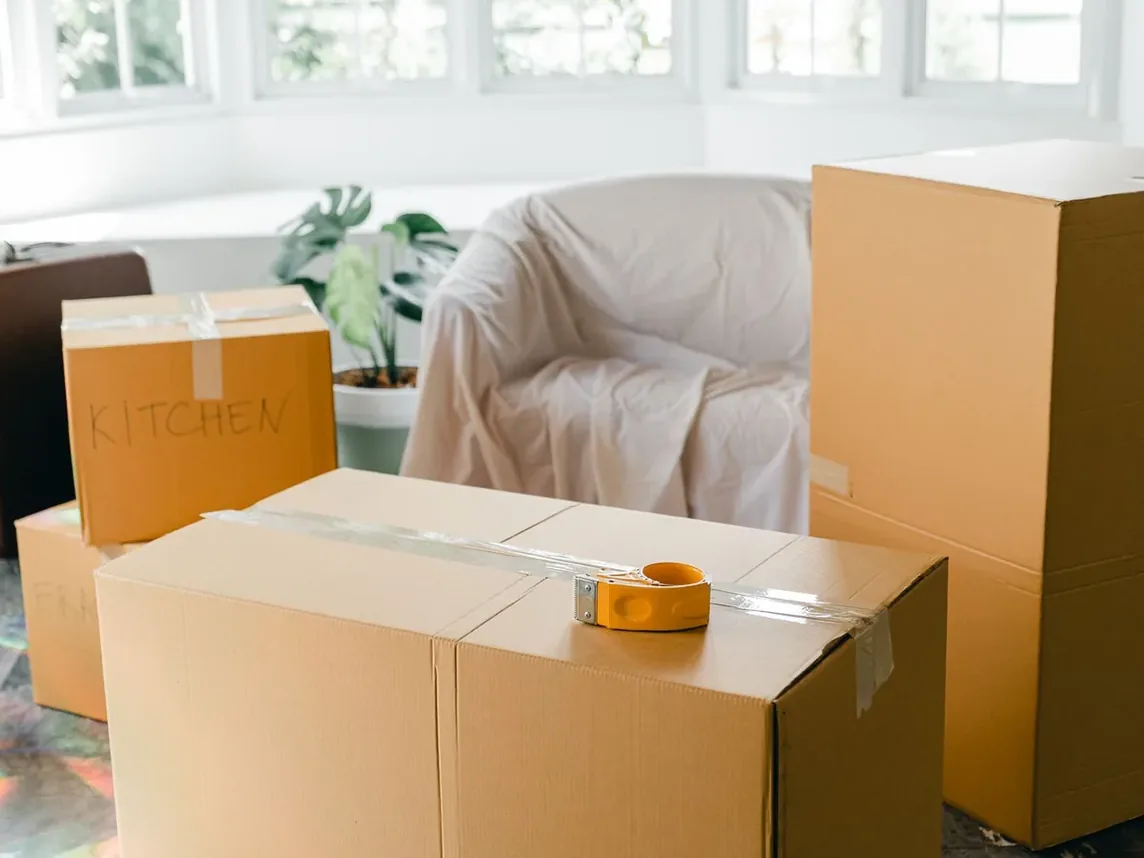 Packed moving boxes and a sheet-covered armchair left in a room during a move