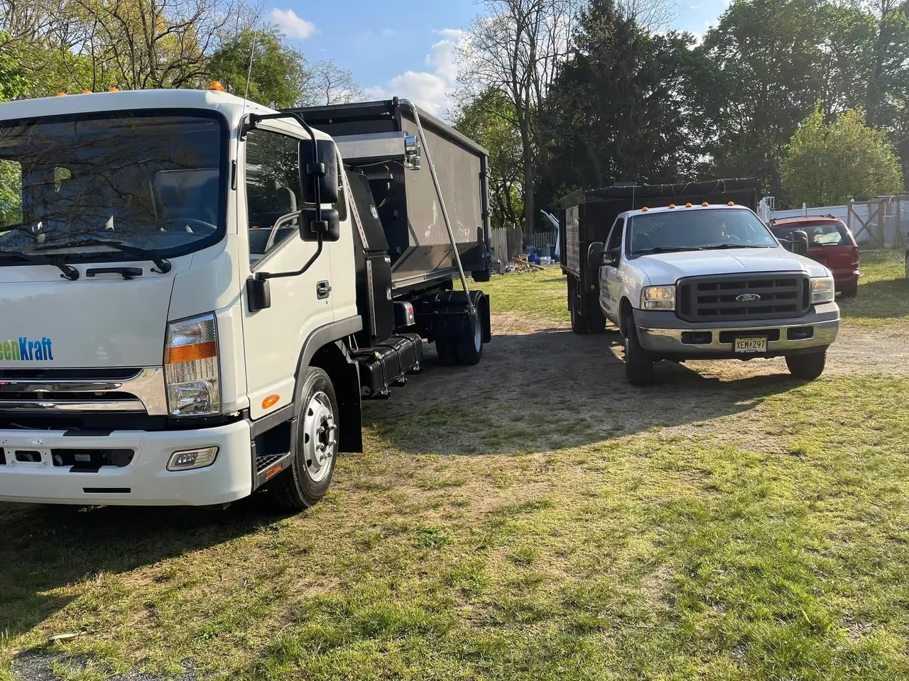 An NJ Indoor Outdoor dump truck and pickup parked at a job site